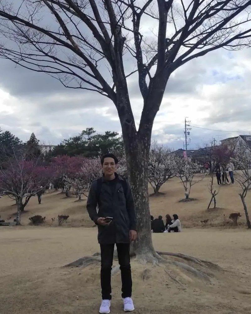 Adam Rabbani Adnan standing under a bare tree in a Japanese park in early spring
